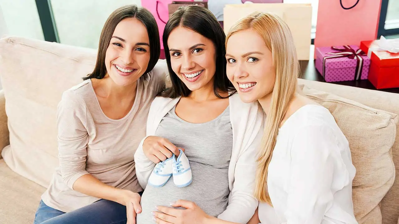 mamás mostrando ropa de bebe en un baby shower